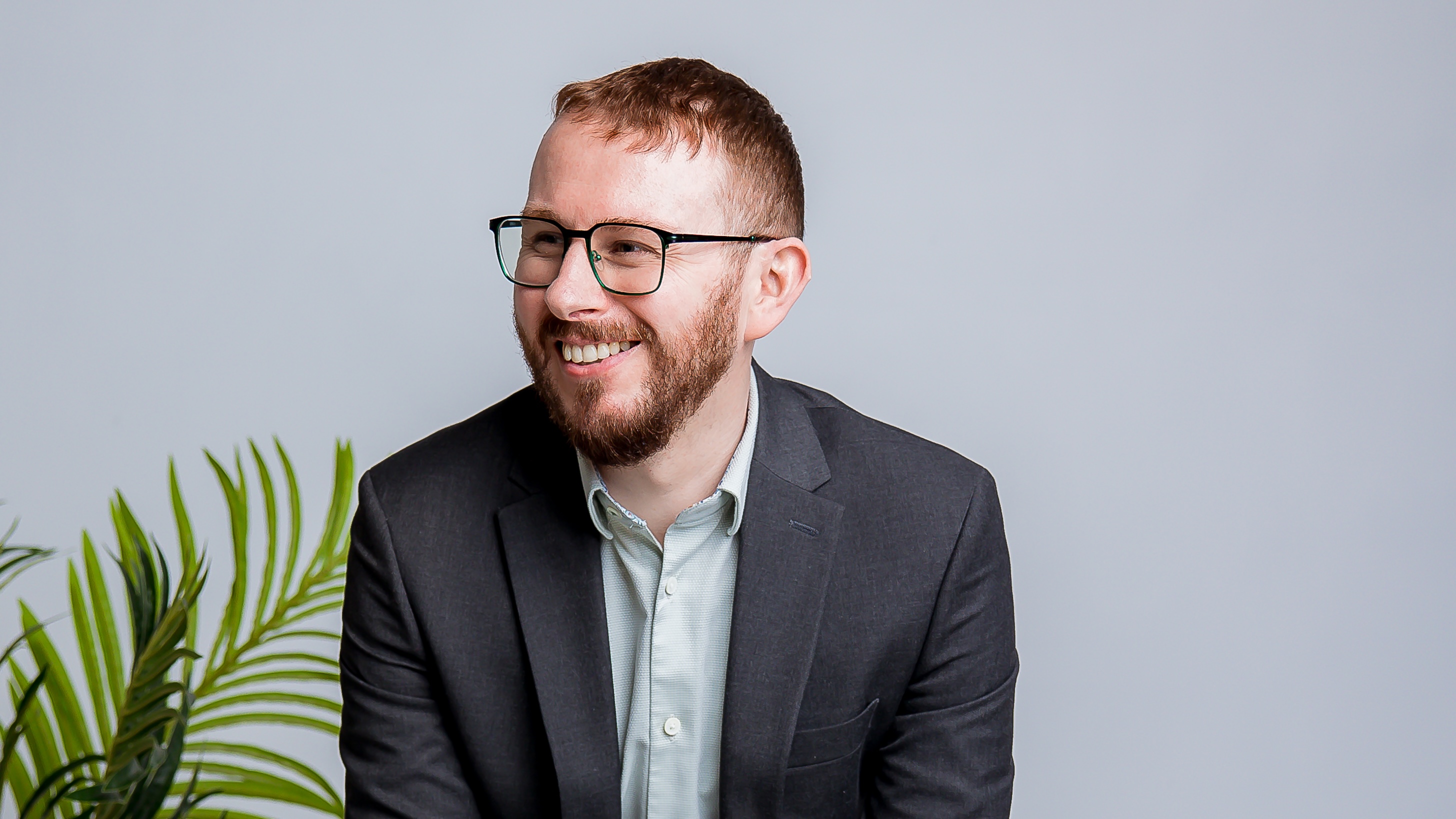 Tom Reveley, cyber security and AI speaker, seated and smiling during a professional photoshoot.